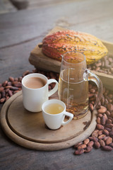 Hot cocoa and milk, Ripe cocoa pod and beans setup on rustic wooden background