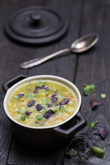 Kartoffelsuppe in schwarzer Cocotte auf dunklem Holz