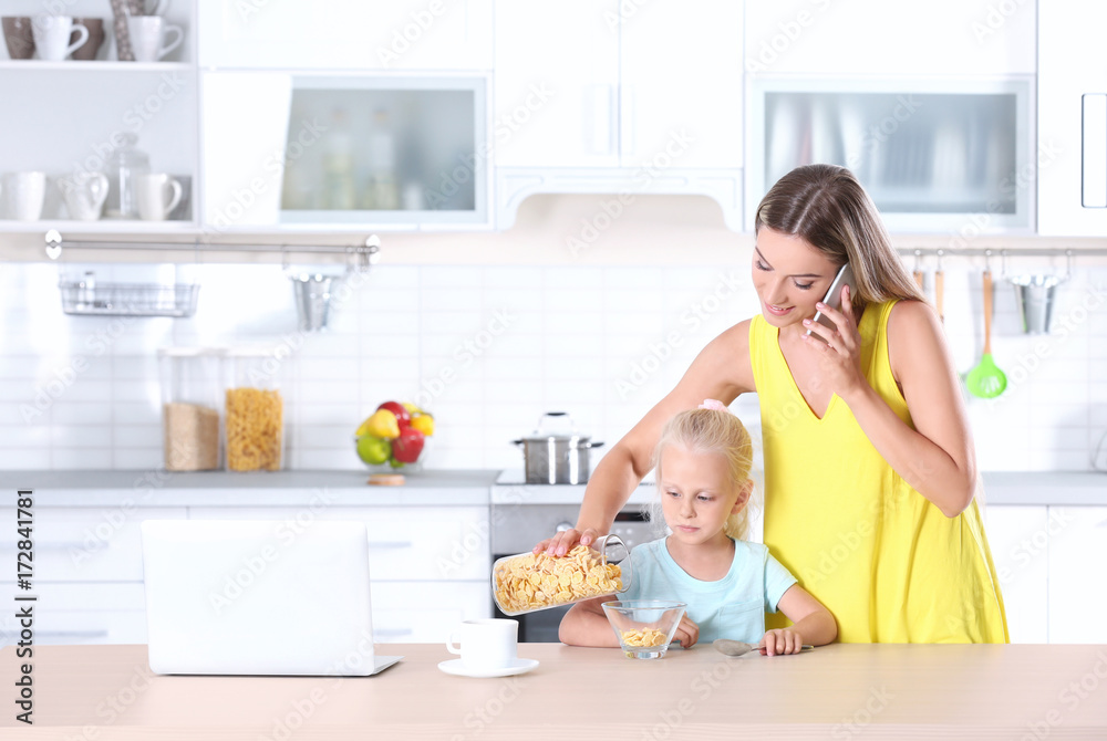 Wall mural busy young woman with her daughter at home