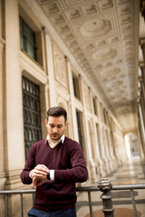 Fototapeta premium Handsome man in casual clothes checking for the time waiting for someone in the city