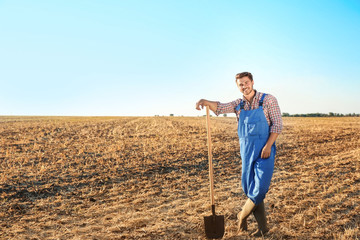 Naklejka na ściany i meble Young male farmer with shovel in field