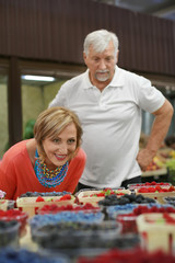 Happy senior couple choosing berries at market