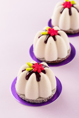 Fototapeta na wymiar Flower shape mini mousse pastry dessert covered with chocolate velour and decorated with glaze