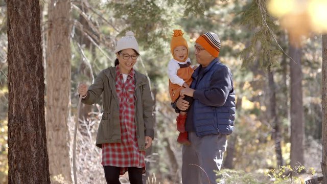 Asian toddler girl walking alone in a forest, front view