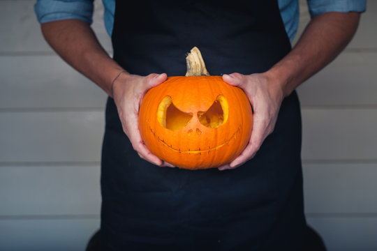 Male hands holding a carved pumpkin