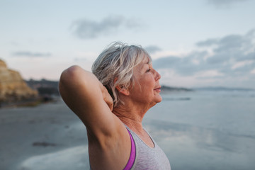 Vibrant mature woman enjoying herself on the beach at sunset