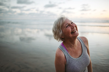 Vibrant mature woman enjoying herself on the beach at sunset