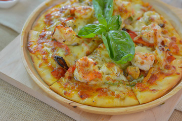 Close-up seafood pizza on wooden plate cutting board style