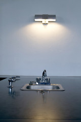 A dimly lit minimalist kitchen sink and bench