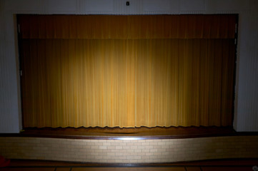 Drawn curtains with spotlight on school stage