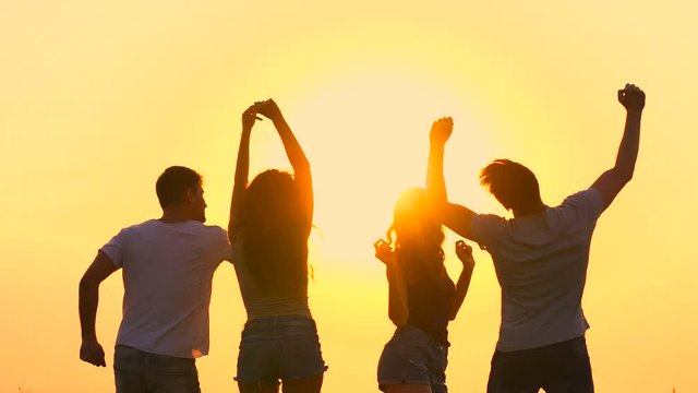 The four people dancing on the background of the sunset. slow motion