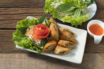 Veg. Spring Rolls on white dish on wooden table.Thai food and selective focus.