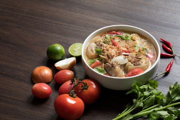 Oxtail soup in white bowl and vegetables for ingredient soup on wooden table.Still life style and Selective focus