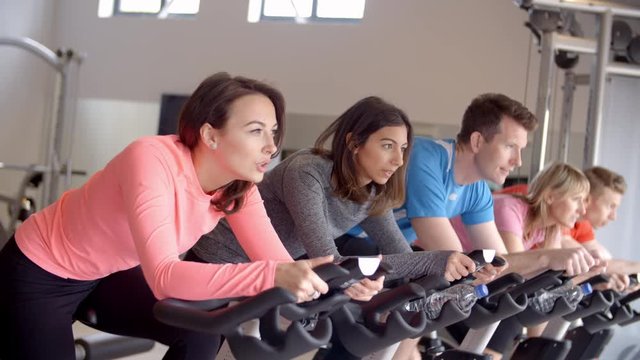 A row of people on exercise bikes in a spinning class at gym