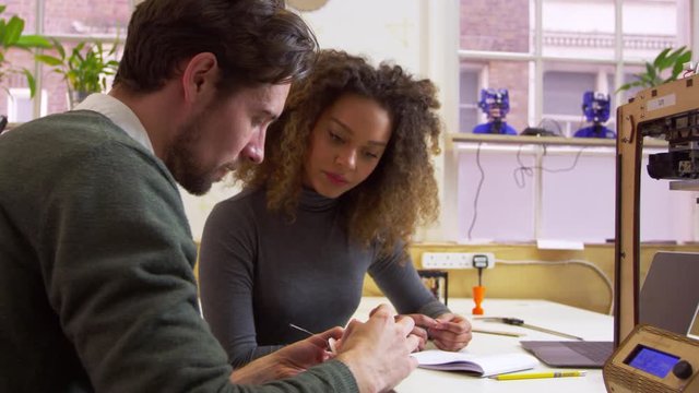 Two designers discussing a prototype in a 3D print lab, shot on R3D