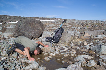 Hiker drinking from mountain spring, Haltitunturi, summer 