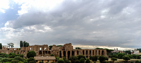 Archaeological ruins of the Severian Arcades on the Palatine and temple of Apollo Palatine with a sky with many clouds. View from the street called "Viale Aventino" in Rome, Italy