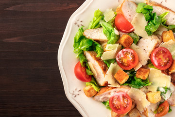 Chicken Caesar salad on dark rustic background with copyspace