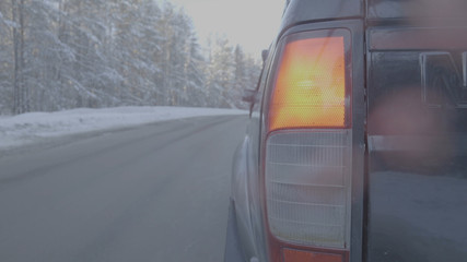Headlight closeup on snowy roads. The car rides on a snow-covered road