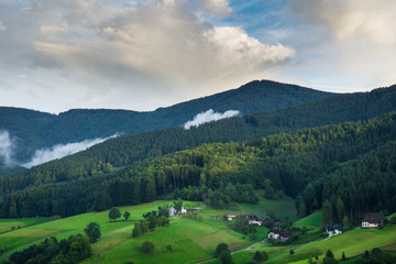 View from above in the black forest Germany near Freiburg with some houses and fog at dawn
