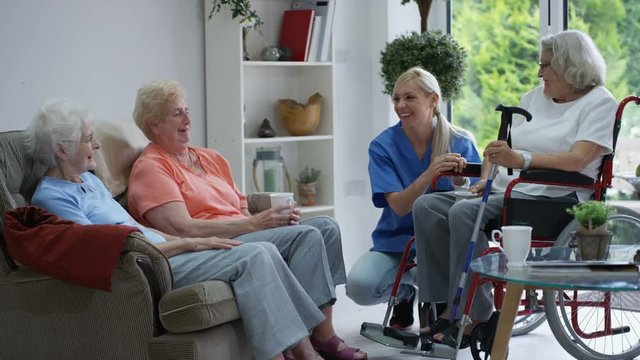 Caring nurse taking care of and talking to elderly residents in a retirement home.