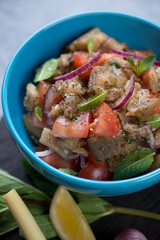 Salad with baked aubergines, fresh tomatoes and mint in a blue bowl, selective focus, close-up, shallow depth of field