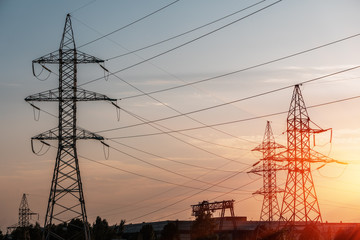 electricity transmission pylon silhouetted against blue sky at dusk.