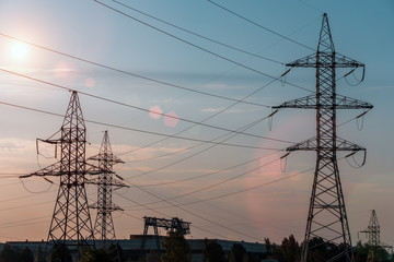 electricity transmission pylon silhouetted against blue sky at dusk.