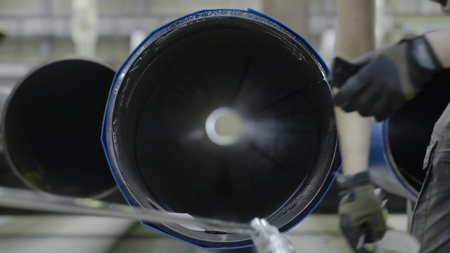 Working on tubular production. Men look inside the pipe