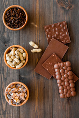 Chocolate with nuts on dark wooden background top view