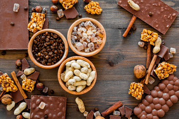 Chocolate with nuts on dark wooden background top view