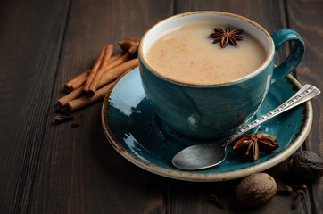 Indian masala chai tea. Spiced tea with milk on dark  wooden background, selective focus.