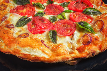 slices pizza with tomato and cheese on black background