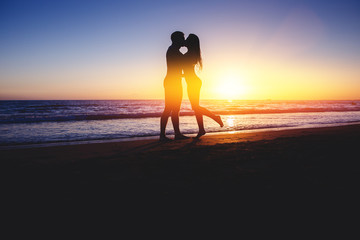 Silhouettes. Blur Couple kissing on beach with beautiful sunset in background