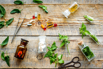 Harvest medicinal herb. Leaves, bottles and sciccors on wooden background top view