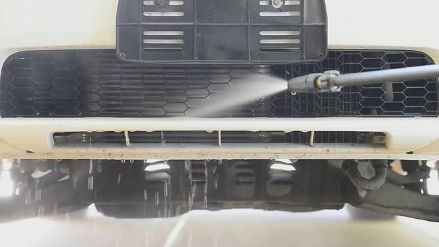 Worker cleaning grille of pick up car with high pressure washer,HD slow motion. 
Car cleaning ,cleaning service concept.
