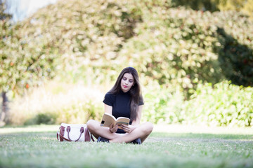 Beautiful young woman reading a book in the pak. Person enjoying reading outdoor