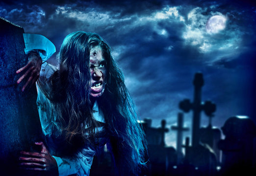 Undead zombie scary girl on halloween graveyard at night on dark clouds sky background. Woman in zombie apocalypse hunting outdoor. Behind monster cemetery with crosses. Moon comes out from clouds