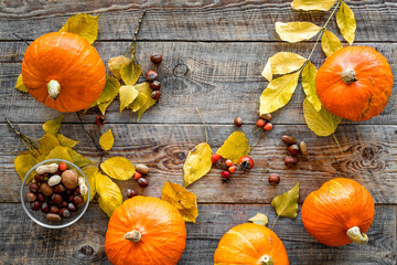 Pumpkin harvest. Pumpkins near nuts and autumn leaves on wooden background top view copyspace