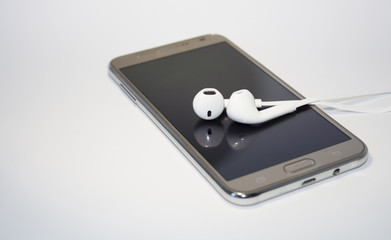 Phone on white background. Smartphone. Mobile phone. Phone with headphones. Headphones for using...