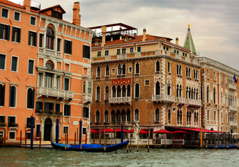 Fototapeta na wymiar Beautiful old bright houses near the canal with gondola in Venice, Italy under blue sky