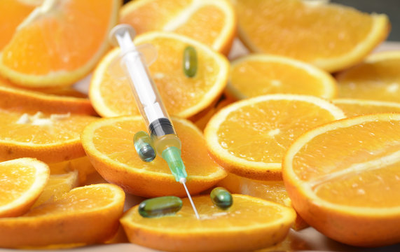 Extrayendo Vitamina C, con una Jeringa de una Naranja Cortada.