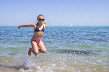teen girl jumping on the beach at blue sea shore in summer vacation at the day time.