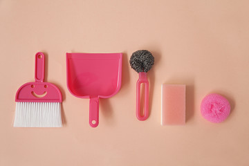 Flatlay collection of pink household cleaning items arranged on pink bacground