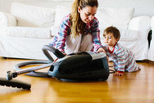 1 year old boy with his mother looking a  vacuum cleaner