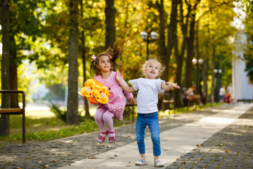 Fototapeta premium two happy little schoolgirls jumping and throwing a backpack