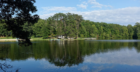 Fototapeta na wymiar Serene park lake panorama: forest, sky, reflection.