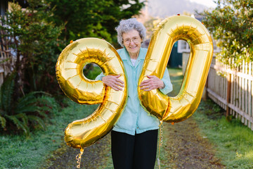 elderly woman holding number balloons for ninetieth birthday