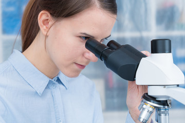 young woman scientific / female student researcher looking microscope  in a laboratory.