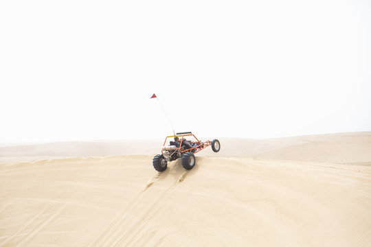 A sand rail catching air as it jumps a sand dune